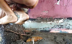 Man shitting and pissing on muddy ground outdoors