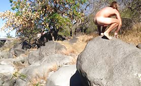 Mature man shitting on big rocks outdoors