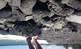 Man shitting outdoors on black rocks