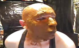 Bald man smears fresh brown shit all over his face