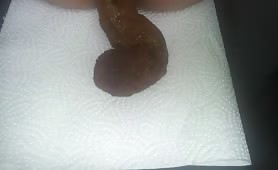 Guy shitting a long brown turd onto a white paper towel