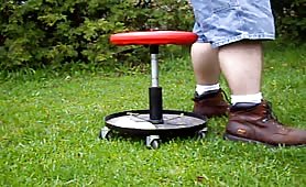 Man shitting outdoors on a rolling stool