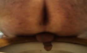 Mature man shitting long yellow turd on toilet