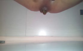 Naked guy shitting long brown turd in shower
