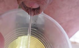 Man pissing into a plastic cup close up
