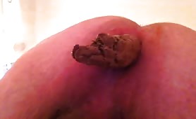 Man shitting long brown turd on his thigh