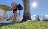 Tattooed ass squats barefoot on grass near tree